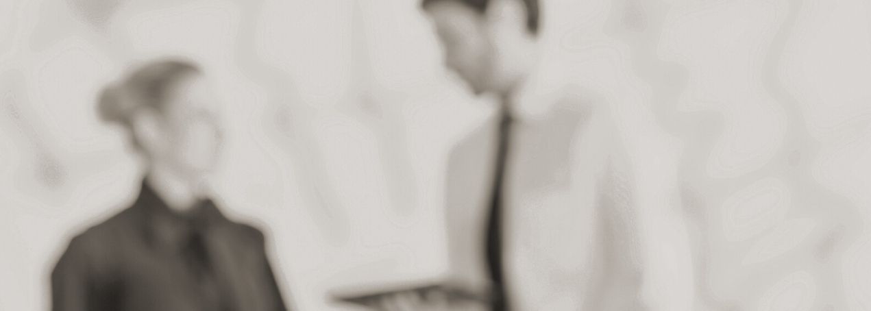 Zwei Personen in formeller Kleidung stehen nebeneinander, eine hält ein Tablet in der Hand