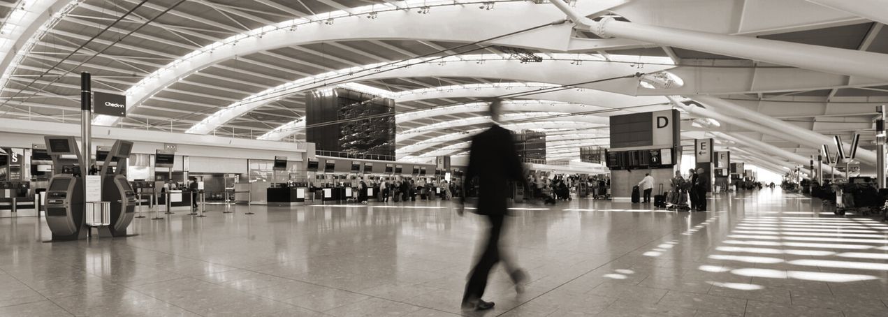 Innenansicht eines modernen Flughafens mit Passagieren und Check-in-Schaltern.